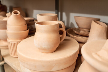 Shelves with bowls, plates, jars, teapots, etc. made in clay in natural raw color until the final painting.