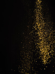 Golden stream of spices in frozen flight on a black background. Aromatic additives, seasonings, spices. Cooking, oriental cuisine, ingredients, flavorings for various dishes. Restaurant, hotel.