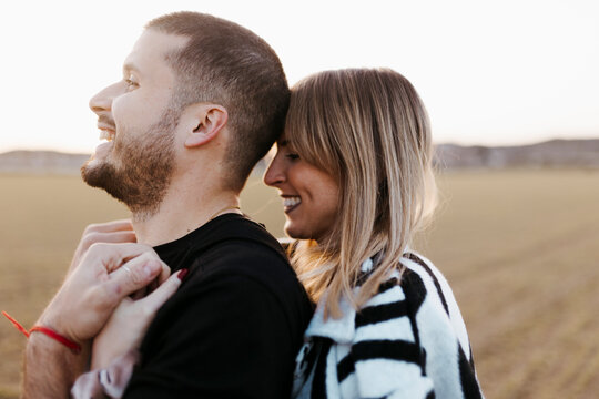 Close up couple hugging and looking at camera in the countryside embraced. Boyfriend and girlfriend in love