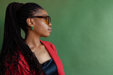 Fashionable elegant Black woman wearing trendy sunglasses, stylish earrings, orange blazer, posing...