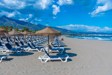 Sunbeds and umbrellas at Playa de Venus at Marbella, Spain. - obrazy, fototapety, plakaty