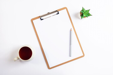 White desktop with clipboard, cup of tea, pencil and succulent plant. Minimal flat lay, top view, mockup