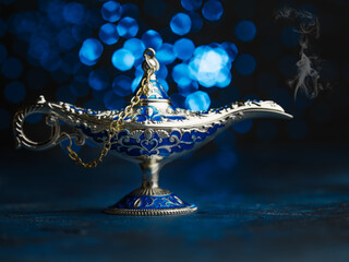 Antique Aladdin lamp inlaid with precious stones on a fantasy blue background. Eastern tales. A...