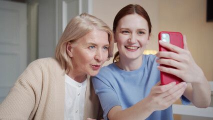 A woman and her grandmother pose for a selfie. They smile and flirt with the camera. Then they look at the resulting pictures
