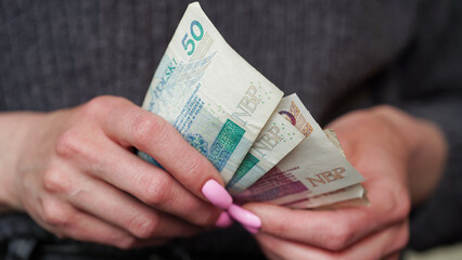 Close-up of female hands holding zloty banknotes, Polish currency. The concept of currency exchange in another country. Tourism and travel. Selective focus.