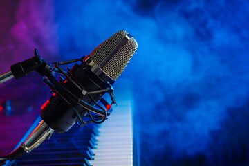 Professional microphone and midi keyboard on a blue smoky background. Concert, vocals, music, nightclub. Entertainment, recreation. There are no people in the photo.