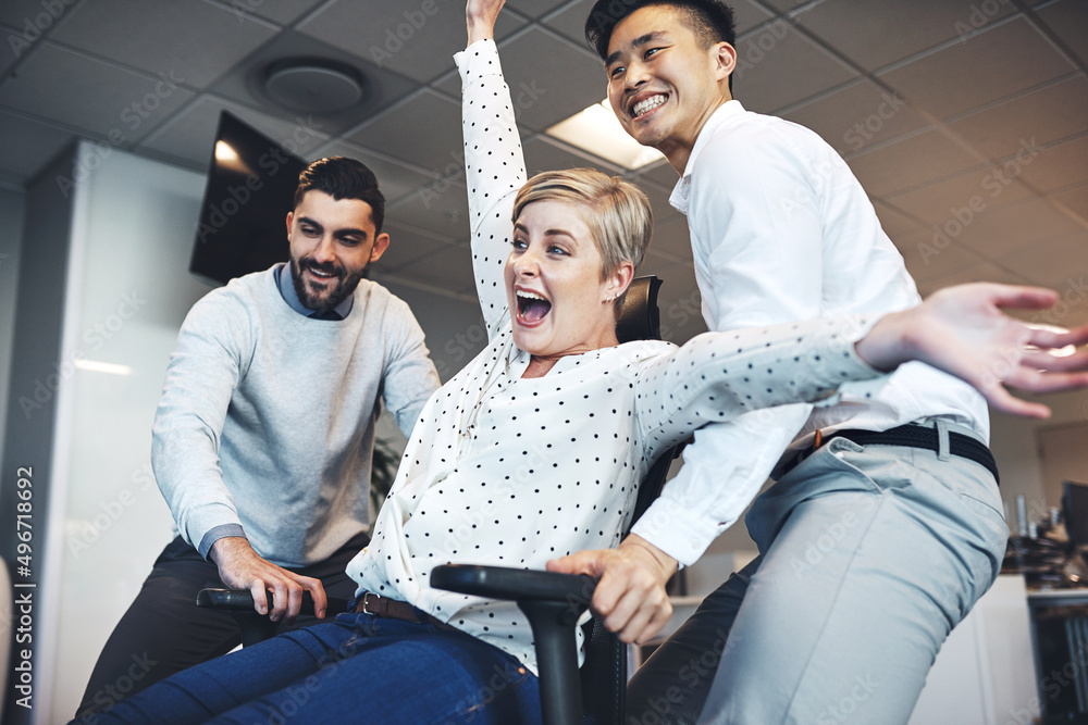 Poster having some colleague fun in the office. shot of businesspeople having fun by pushing taking their c