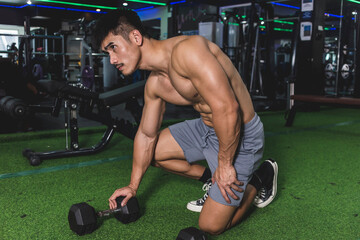 A shirtless man kneeling and mentally preparing himself before a set of weight training. Working...