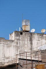 Obraz premium old water tanks and satellite dishes on the roofs of houses. on top of buildings.