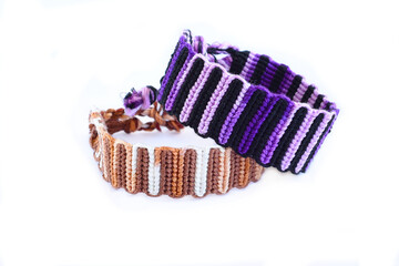 Tied DIY friendship bracelet with unusual braiding pattern on white background