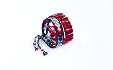 Tied DIY friendship bracelet with unusual braiding pattern on white background