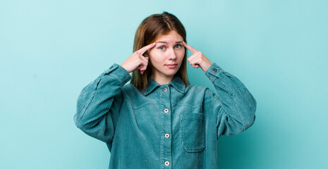 red head pretty woman with a serious and concentrated look, brainstorming and thinking about a...