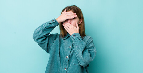 red head pretty woman covering face with both hands saying no to the camera! refusing pictures or...