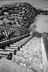 Cement steps and railing to the ocean in black and white.
