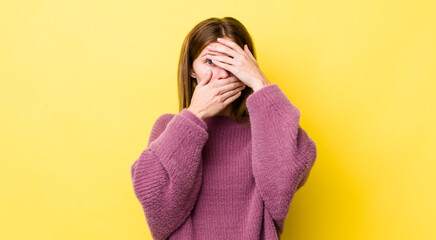 red head pretty woman covering face with both hands saying no to the camera! refusing pictures or...
