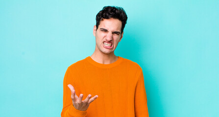 handsome hispanic man looking angry, annoyed and frustrated screaming wtf or what’s wrong with you