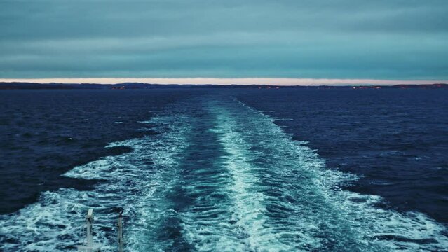 Wake In Sea Left By Ferry Leaving Coastline At Dusk