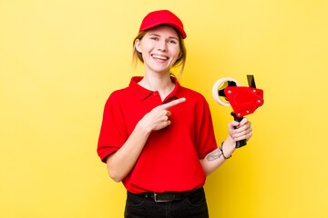 red head pretty woman smiling cheerfully, feeling happy and pointing to the side. packer concept