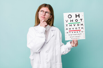 red head pretty woman thinking, feeling doubtful and confused. optical vision test concept