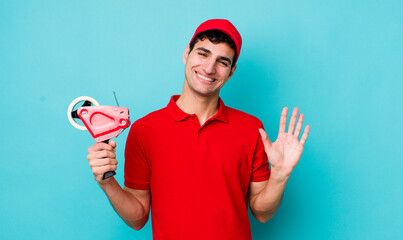 handsome hispanic man smiling happily, waving hand, welcoming and greeting you. packer concept