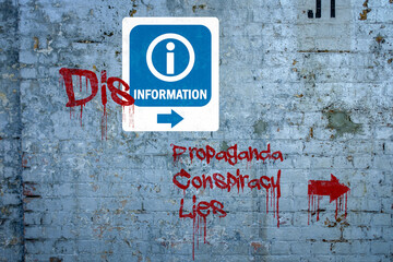 Disinformation graffiti on information sign, propaganda, conspiracy, lies spray painted on wall,...
