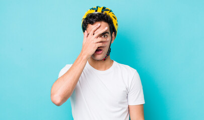 handsome hispanic man looking shocked, scared or terrified, covering face with hand. bike concept