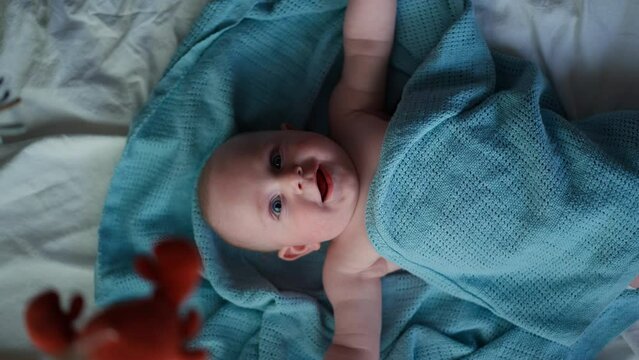 Little cute causian baby boy, smiling at camera, boy looks at the toy and is delighted. vertical video