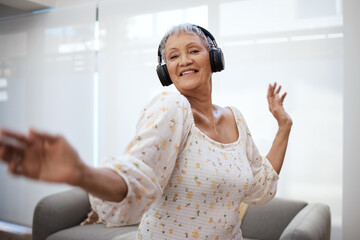 Every time you dance, you defy your age a little more. Shot of a senior woman dancing while using headphones at home. - Powered by Adobe