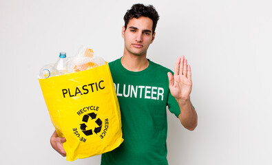 handsome hispanic man looking serious showing open palm making stop gesture. ecology concept