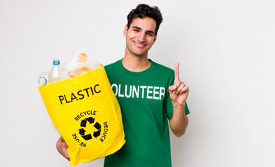 handsome hispanic man smiling and looking friendly, showing number one. ecology concept