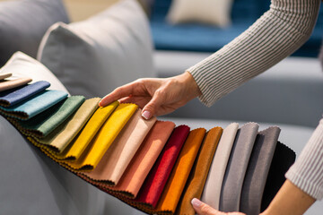 The woman chooses the fabric on the sofa. A young women looks at tissue samples. Selects the color of the sofa. Textile industry background. Tissue catalog