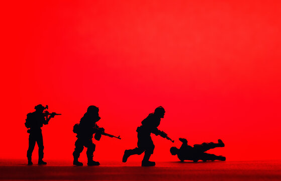 Silhouetted toy army plastic soldiers organised with a red background, war image