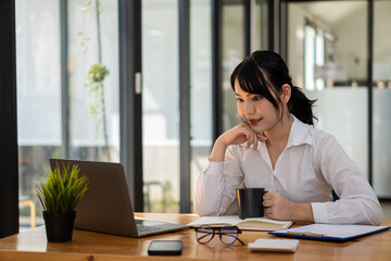 Asian women Work on laptops, computers, and tiger skins at the desk. Small business owners, employees, online, freelance, SME marketing, eCommerce, finance, office marketing ideas.