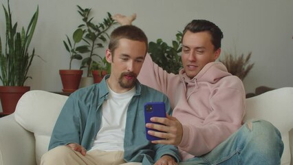 Two adult attractive lgbt men are talking to their friends about their flat interior on the video call