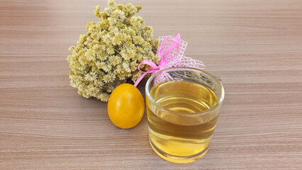 Macela tea (achyrocline satureioides) served in the cup, a bouquet of Macela flower and a colored Easter egg on the side. Macela, medicinal plant, natural, traditionally harvested on the eve of Easter