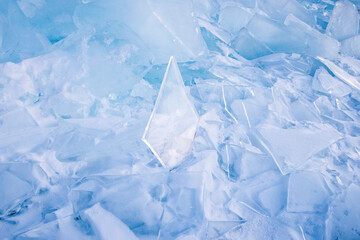 Cracked blue transparent ice glow in the sun light on the lake Baikal. Winter ice, blue ice background