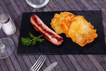 Traditional Belarusian dish is potato draniki with fried sausage and decorated a sprig of dill
