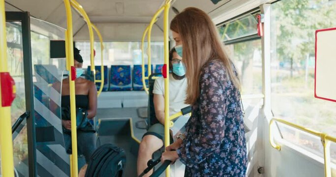A young woman takes a bus with child on a summer morning, gets off at the bus stop, a man helps the girl pull the baby carriage out of the public transport vehicle