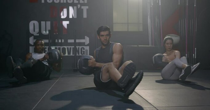 Young muscular athletic group doing training abdomen exercises working out with a medicine ball in fitness gym, strength workout healthy lifestyle sport concept