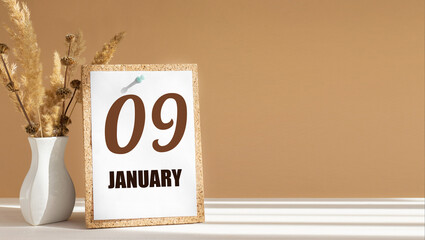 january 9. 9th day of month, calendar date.White vase with dead wood next to cork board with numbers. White-beige background with striped shadow. Concept of day of year, time planner, winter month