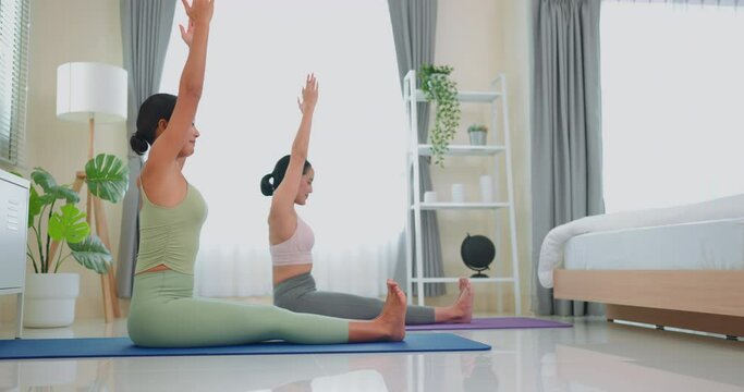 Female trainer coaching senior woman doing yoga at home.