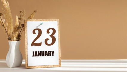 january 23. 23th day of month, calendar date.White vase with dead wood next to cork board with numbers. White-beige background with striped shadow. Concept of day of year, time planner, winter month