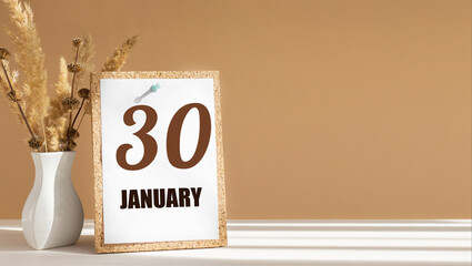 january 30. 30th day of month, calendar date.White vase with dead wood next to cork board with numbers. White-beige background with striped shadow. Concept of day of year, time planner, winter month