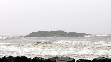 Wave in the surf behind a small nearshore island during a huge storm event with very heavy rain and overcast sky. - Powered by Adobe