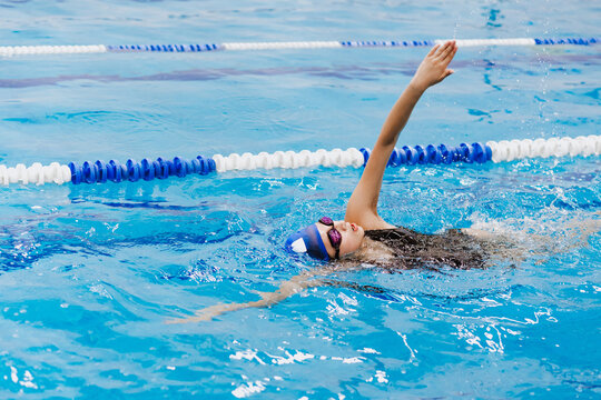hispanic teenager girl swimmer athlete wearing cap and goggles in a swimming training at the Pool in Mexico Latin America	