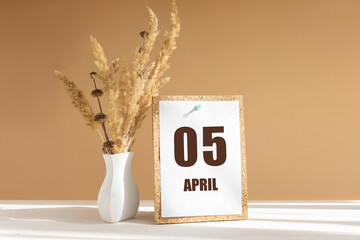 April 5. 5th day of month, calendar date.White vase with dried flowers on desktop in rays of sunlight on white-beige background. Concept of day of year, time planner, spring month