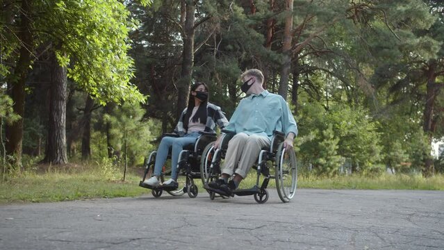 Two disabled young friends are walking in the forest and talking to each other, slow motion