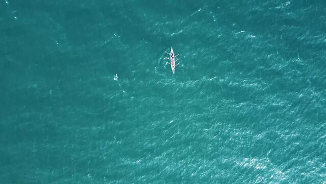 Solo Rowing boat out at Sea, off the coast of the United Kingdom on a sunny day, filmed with a DJI mavic drone, which is directly above, alienating the single boat.