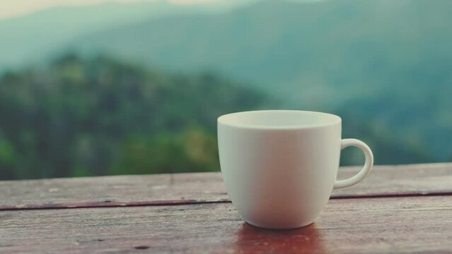 B-roll - Morning coffee or tea on wooden table with mountain view background.