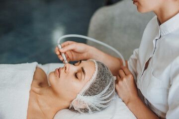 Doctor cosmetologist performing aqua peeling on patient face for remove dead damaged cells....